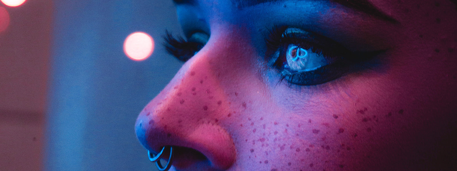 Close-up of a person's face with a blurred background and colorful lighting